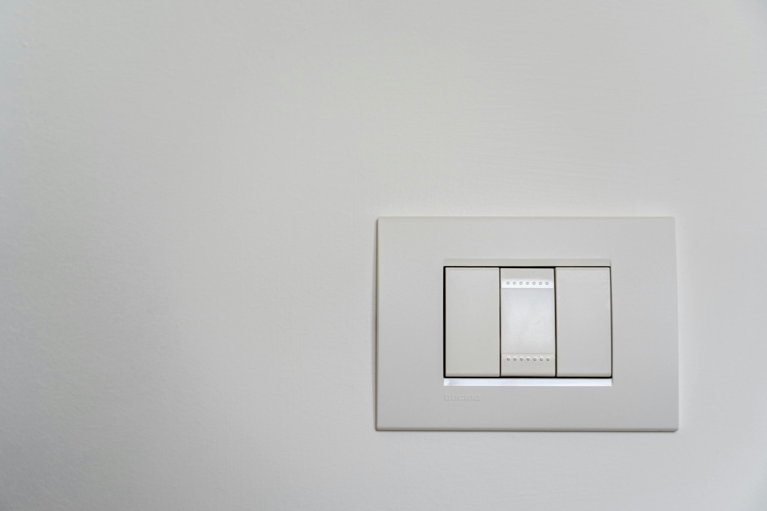 Close-up of a modern white light switch on a clean wall.